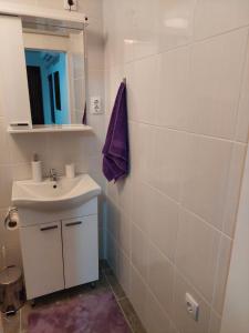 a white bathroom with a sink and a mirror at Apartman Centar in Kragujevac