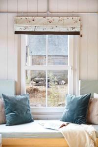 a window with a couch in front of it with a window shade at Aileen - Unique tiny house with wood fired roll top bath in heart of the Cairngorms in Ballater