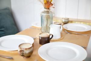 a table with plates and cups and a vase at Aileen - Unique tiny house with wood fired roll top bath in heart of the Cairngorms in Ballater