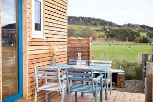 a table and chairs on a patio with a field at Aileen - Unique tiny house with wood fired roll top bath in heart of the Cairngorms in Ballater