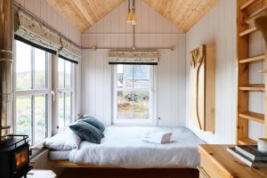 a bedroom with a bed in a room with windows at Aileen - Unique tiny house with wood fired roll top bath in heart of the Cairngorms in Ballater