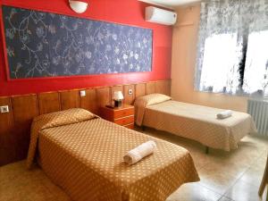 a room with two beds and a painting on the wall at Hostal Isla Cristina Mataro in Mataró