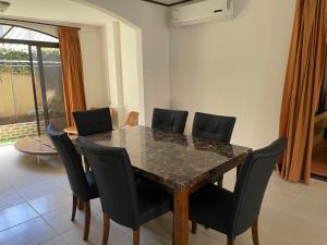 uma sala de jantar com uma mesa de mármore e cadeiras em Family oriented house just steps to the beach em Jacó
