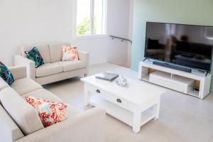 ein Wohnzimmer mit 2 Sofas und einem Flachbild-TV in der Unterkunft Villa du Marché in Royan