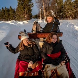 two women and a man on a horse drawn sleigh at Flatmoen Natur Lodge in Alta