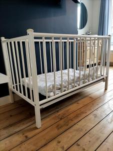 a white crib in a room with a wooden floor at La Roche ô Tour! - Gîte citadin in La-Roche-en-Ardenne
