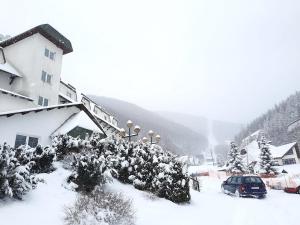 ein schneebedecktes Haus mit einem daneben geparkt in der Unterkunft Apartman Pod bregom - Gondola 180m in Brzeće