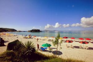 カボ・フリオにあるEXCELENTE CASA EM CABO FRIO - BRAGAの傘がたくさんの人々が乗る浜