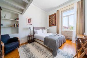 a bedroom with a bed and a blue couch and a window at Casa do Cativo in Porto