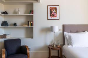 a bedroom with a bed and a chair and a lamp at Casa do Cativo in Porto