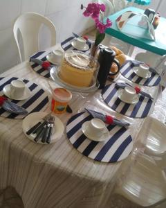 une table avec un gâteau sur un tissu de table rayé bleu et blanc dans l'établissement Pousada Restaurante Sol de Liz, à Fortaleza