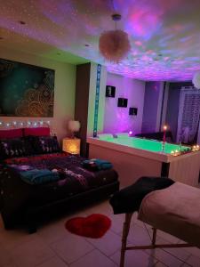 a bedroom with a bed and a tub with purple lighting at Loft avec Baignoire SPA LÉcrin Romantique in Ochancourt