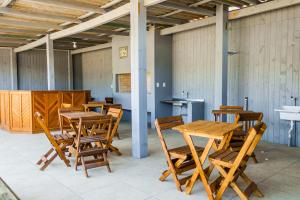 a group of wooden tables and chairs in a room at Residencial Primo in Capão da Canoa