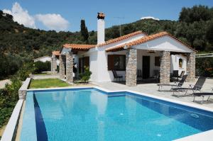 a villa with a swimming pool in front of a house at Skiathos Island Villas in Skiathos