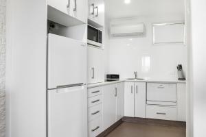 a white kitchen with white cabinets and a refrigerator at The Duck Inn Apartments in Tamworth