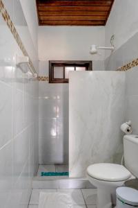 een witte badkamer met toilet en douche bij Suítes Casa do Barão in Búzios