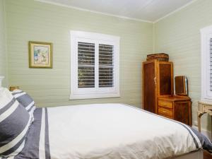 a bedroom with a bed and a dresser and a window at Witts Oasis Two traditional Tea Gardens cottages in Tea Gardens