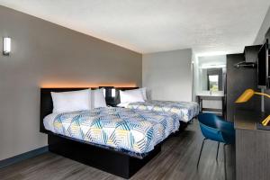Pokój hotelowy z 2 łóżkami i niebieskim krzesłem w obiekcie Studio 6 Meridian, MS Bonita Lakes w mieście Meridian