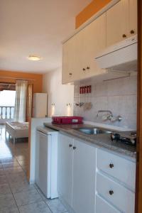 a kitchen with white cabinets and a sink at Elena Studios in Patitiri
