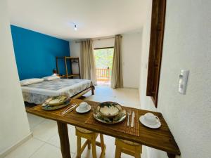 ein Zimmer mit einem Bett und einem Tisch mit Tellern darauf in der Unterkunft Loft Reserva Sapiranga Praia do Forte Vila Hen 102 in Mata de Sao Joao