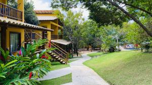 una pasarela junto a una casa amarilla con patio en Loft Reserva Sapiranga Praia do Forte Vila Hen 102 en Mata de Sao Joao