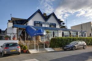 a building with two cars parked in front of it at BEST WESTERN New Holmwood Hotel in Cowes