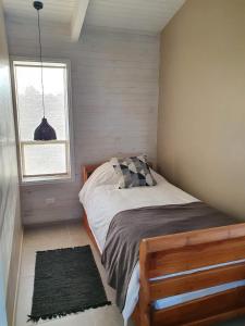 a small bedroom with a bed with a window at CABAÑA NORDICA in Los Laureles