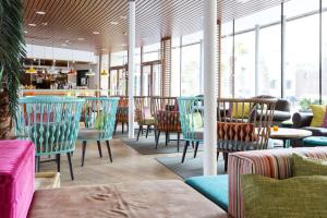 a restaurant with colorful chairs and tables and windows at Scandic The Reef in Frederikshavn