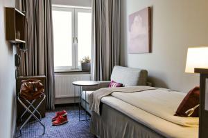 a hotel room with a bed and a chair and a window at Scandic No. 25 in Gothenburg