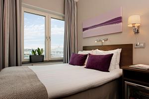 sypialnia z łóżkiem z fioletowymi poduszkami i oknem w obiekcie Scandic No. 25 w Göteborgu