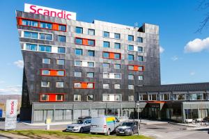 un gran edificio con coches estacionados en un estacionamiento en Scandic Elmia en Jönköping