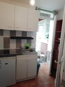- une cuisine avec des placards blancs et un évier dans l'établissement Charmant Appartement 10mn Rouen, à Franqueville-Saint-Pierre
