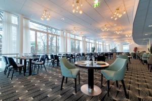 a dining room with tables and chairs and windows at Scandic Linköping City in Linköping