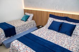 ein Schlafzimmer mit zwei Betten mit blauen Kissen in der Unterkunft Flat em Guarajuba in Guarajuba + 36 Fotos