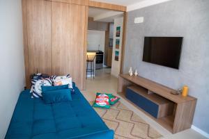 ein Wohnzimmer mit einem blauen Sofa und einem Flachbild-TV in der Unterkunft Flat em Guarajuba in Guarajuba