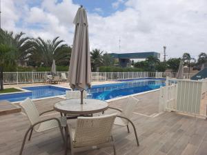 a table and chairs with an umbrella next to a pool at Fantástica casa 4 quartos próxima a praia em condomínio fechado ! in Aracaju