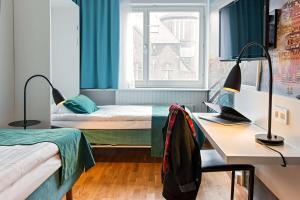 a bedroom with two beds and a desk and a window at Scandic Sjöfartshotellet in Stockholm