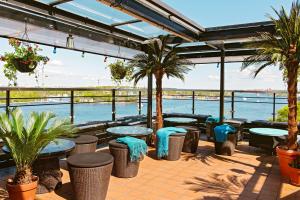 a patio with tables and palm trees and the water at Scandic Sjöfartshotellet in Stockholm
