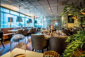 a dining room with tables and chairs and windows at Scandic Sjöfartshotellet in Stockholm