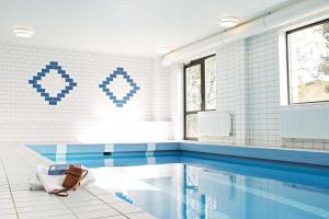 a bathroom with a swimming pool and blue tiles at Scandic Sundsvall Nord in Sundsvall