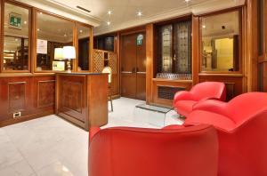 ジェノヴァにあるベスト ウェスタン ホテル モデルノ ヴェルディの赤い椅子とデスクが備わる待合室