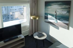 a living room with a television and a large window at Scandic Ishavshotel in Tromsø