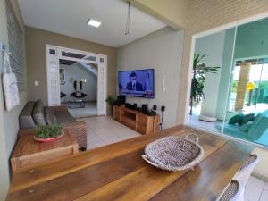 a living room with a table and a television at Linda casa de praia em Aracaju! in Aracaju