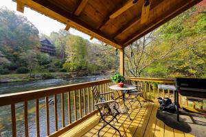 a porch with a table and a grill and a river at Rushing River in Ellijay