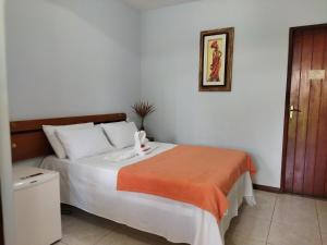 um quarto com uma cama com um cobertor laranja em Morada Toniatti em Barra Grande