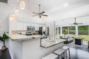 a kitchen and living room with white walls and a ceiling fan at The Bonita Rita - Magnum in Bonita Springs