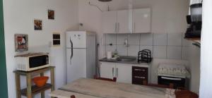 cocina con nevera y mesa con microondas en Village Acapulco - Itacimirim/BA, en Itacimirim