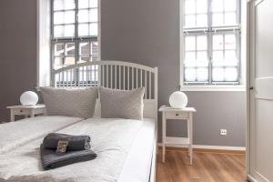 a bedroom with a white bed with two windows at Ferienwohnungen BUNTER HOF Quedlinburg in Quedlinburg