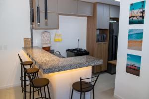 a kitchen with a counter with stools around it at Flat em Guarajuba in Guarajuba