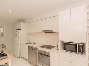 a white kitchen with a microwave and a refrigerator at Edge 6 16 Clyde Street in Jindabyne